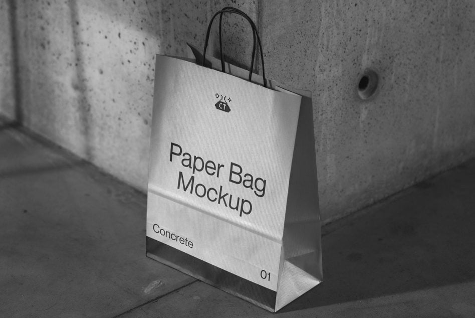 White paper shopping bag with black handles on concrete floor